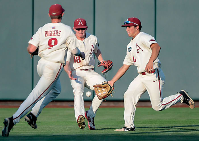 Arkansas Razorbacks shortstop Jax Biggers (9) and left fielder Heston Kjerstad (18) and center fielder Dominic Fletcher (24) converge on a ball in the game against the Oregon State Beavers in game 3 of the College World Series at TD Ameritrade Park. Arkansas dropped a similar pop-up in the previous game that would have clinched the championship.